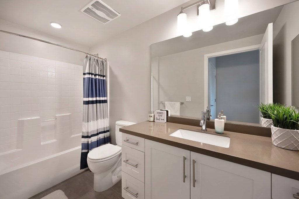 A bathroom with a toilet, sink, and mirror.