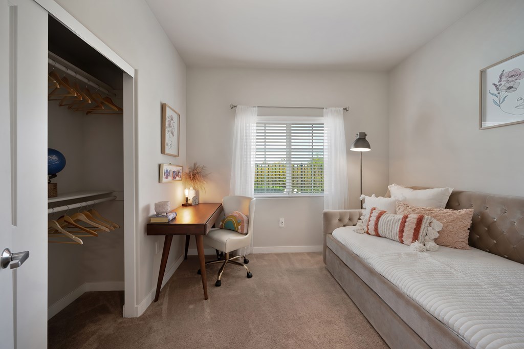 A bedroom with a bed, desk, and chair.