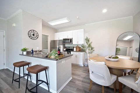 A kitchen with a bar area and a dining table with chairs.