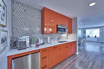 A kitchen with orange cabinets and a silver dishwasher.