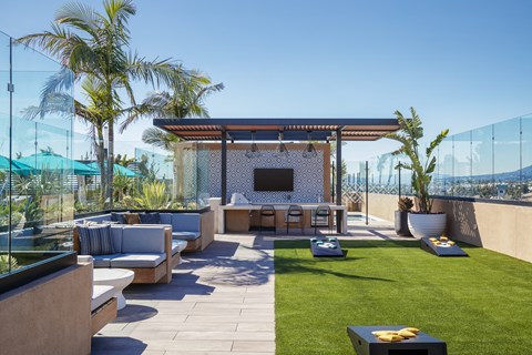 an outdoor lounge area with a bar and a flat screen tv on a pergola