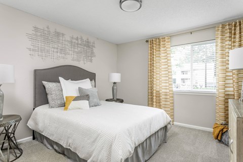 A bedroom with a large bed and a window with curtains.