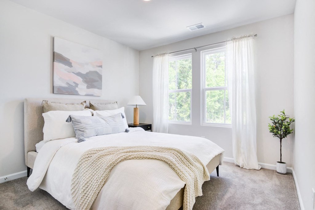 a bedroom with a bed and two windows Brightly lit bedroom at Berkeley Homes