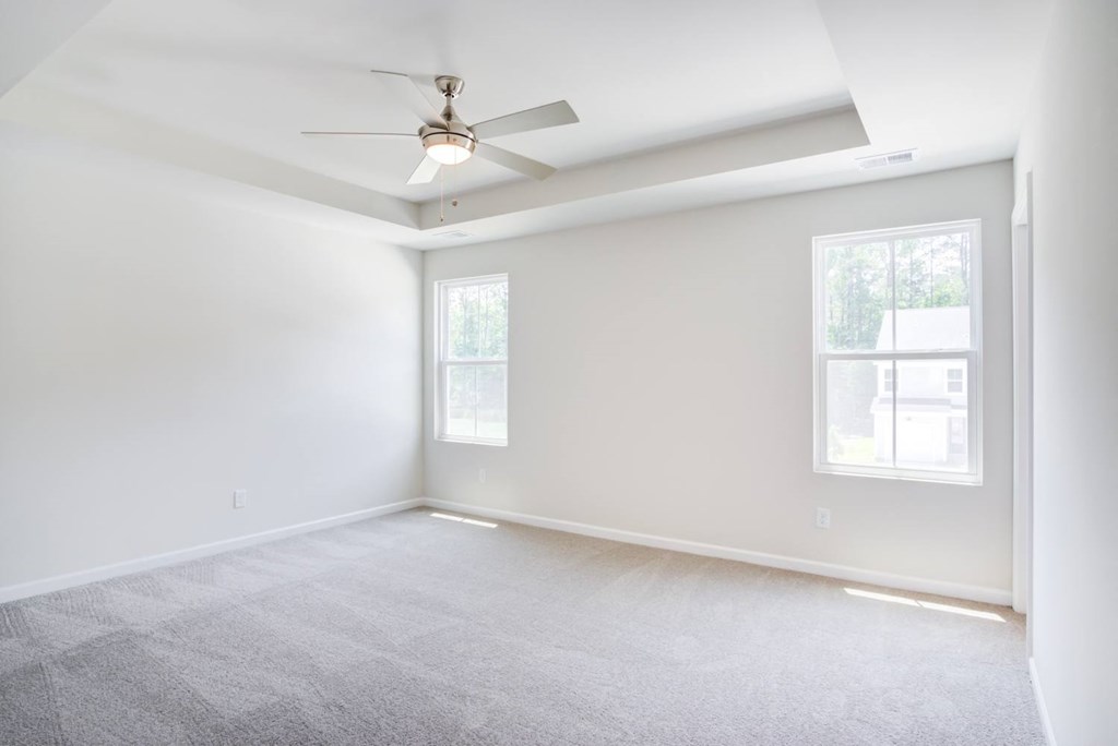 an empty room with a ceiling fan and two windows at Berkeley Homes, Moncks Corner