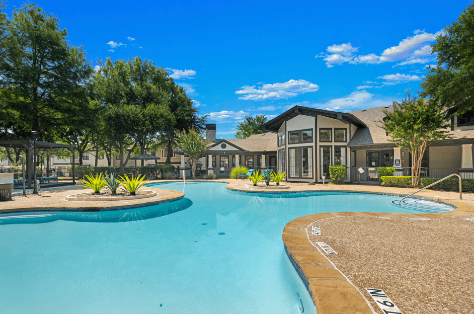 A large swimming pool in front of a building with trees around it.