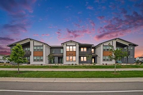 A modern apartment building with a green lawn in front.