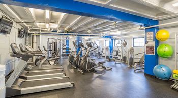 a large fitness room with cardio equipment and weights