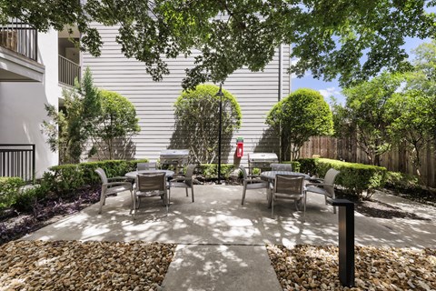 A patio with chairs and a table surrounded by a stone border.