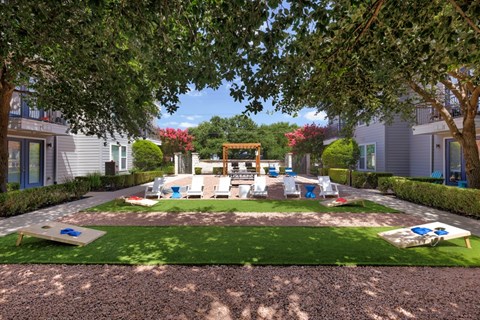A playground area with a slide and swings surrounded by trees and houses.