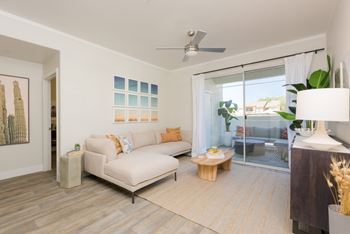 A living room with a white couch and a painting on the wall.