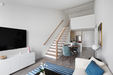 a living room with a staircase and a dining table in a 555 waverly unit