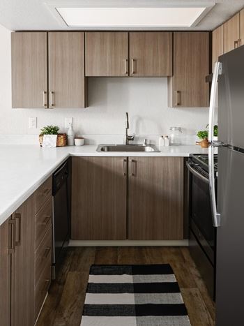 A kitchen with wooden cabinets and a black and white striped rug.