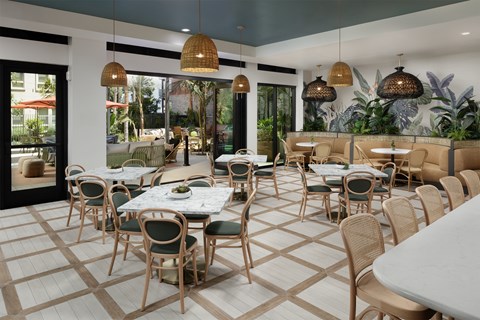 A restaurant with tables and chairs and a view of the outside.