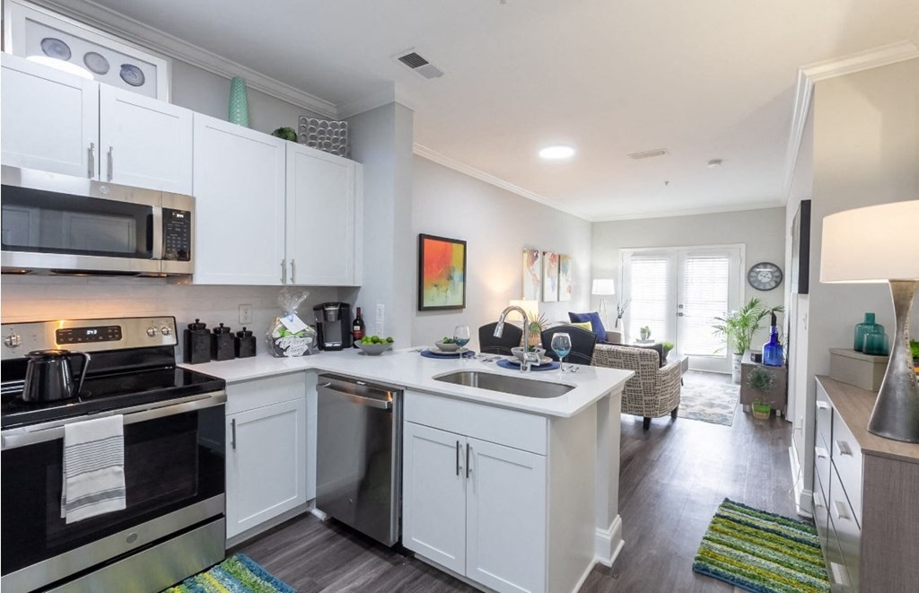 a kitchen and living room with white cabinets and stainless steel appliances
