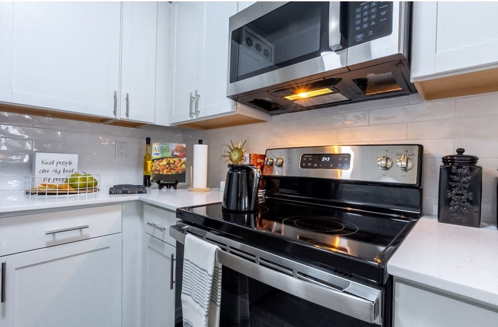 a kitchen with white cabinets and a stove and microwave