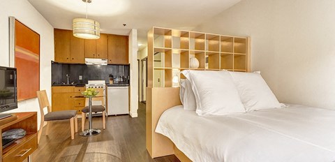 a bedroom with a bed and a kitchen in the background