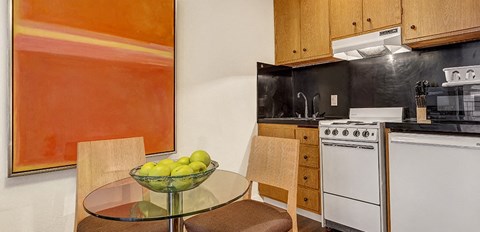 a kitchen with a white stove top oven next to a table with a bowl of fruit on