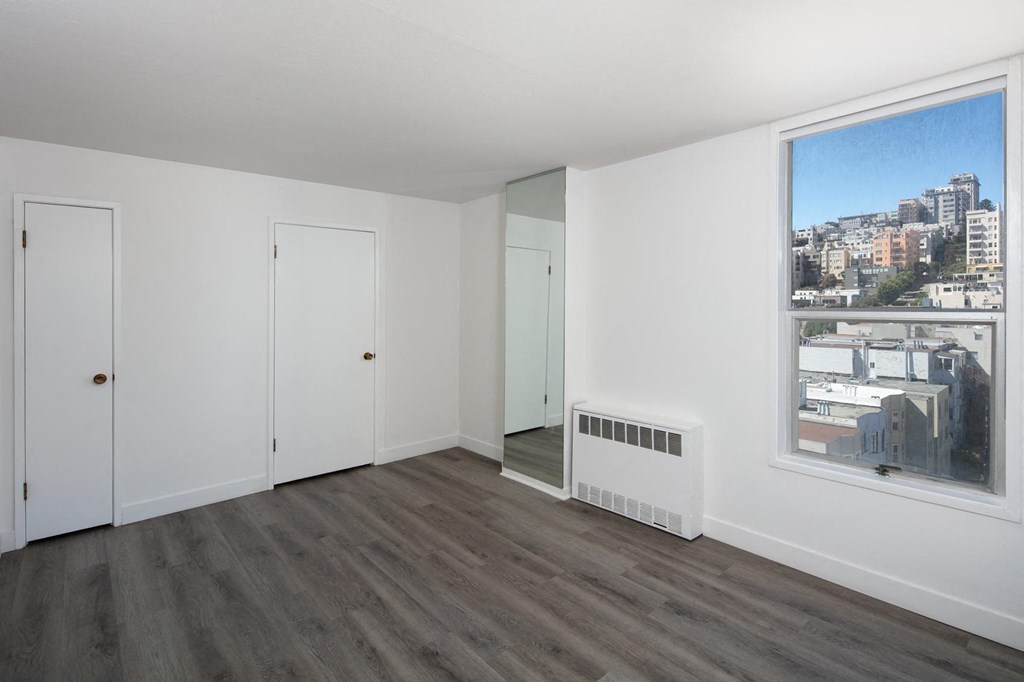 a bedroom with hardwood floors and white walls