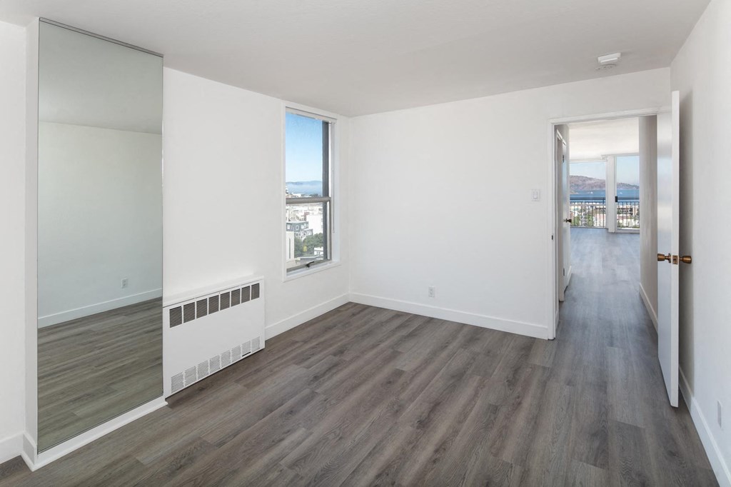 a bedroom with hardwood floors and white walls