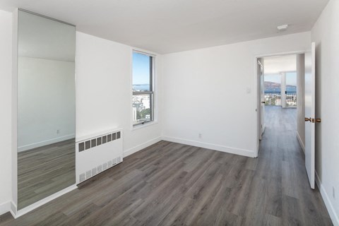 a bedroom with hardwood floors and white walls