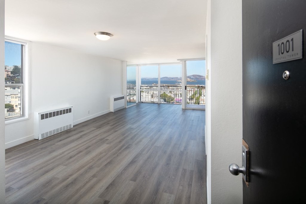 an open living room with hardwood floors and a balcony