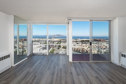 an open living room with hardwood floors and a balcony with a view of the city
