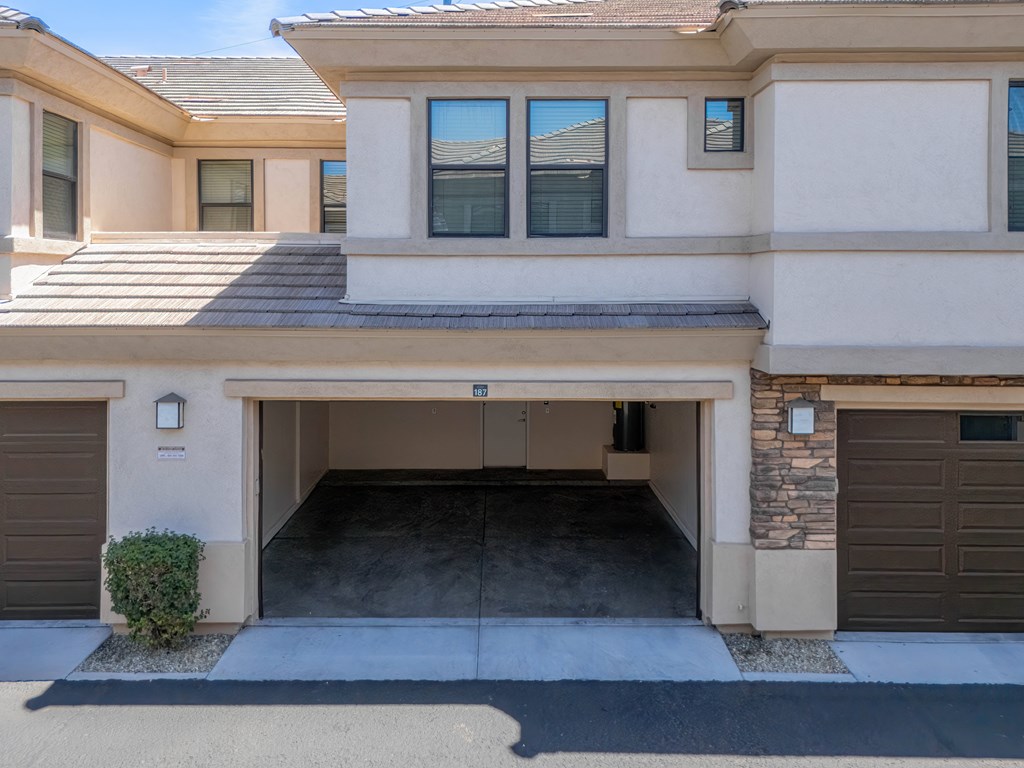 A two-story house with a garage door open.
