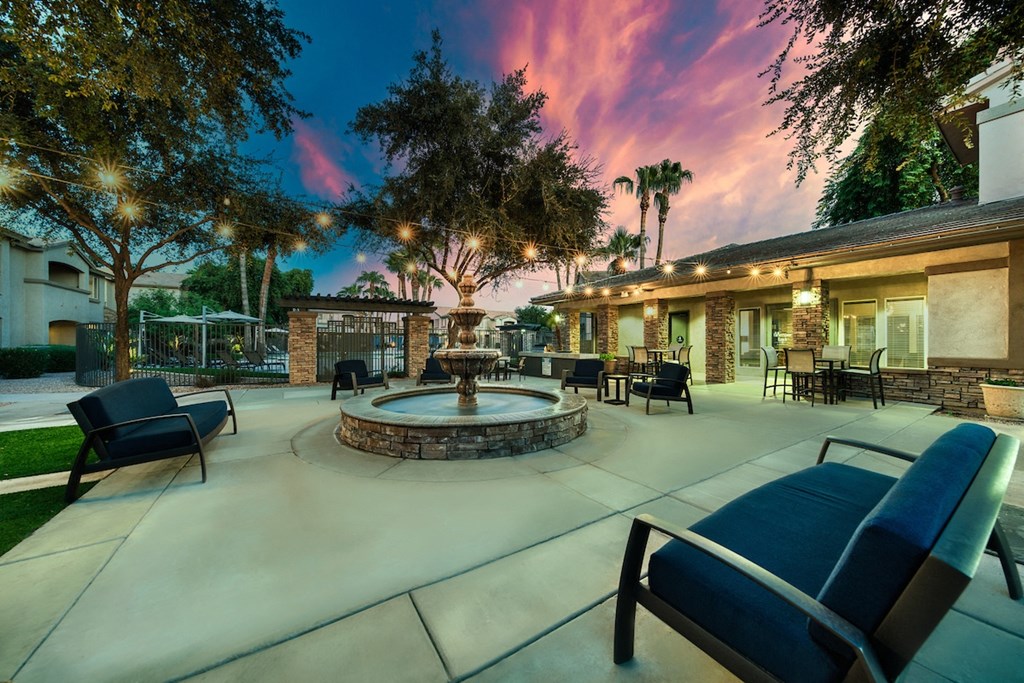 A patio with a fire pit and chairs.