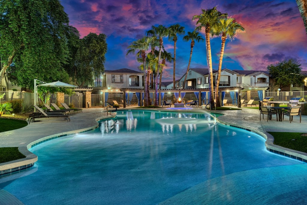 A swimming pool surrounded by palm trees and a house in the background.