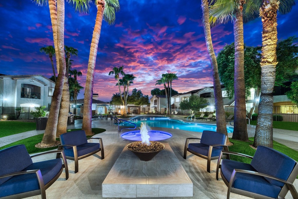 A pool surrounded by palm trees and lounge chairs.