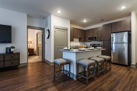 A kitchen with a bar stool and a refrigerator.