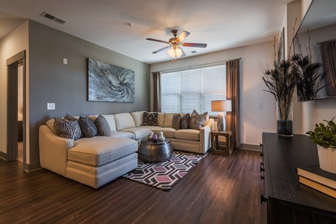 A living room with a white couch and a ceiling fan.