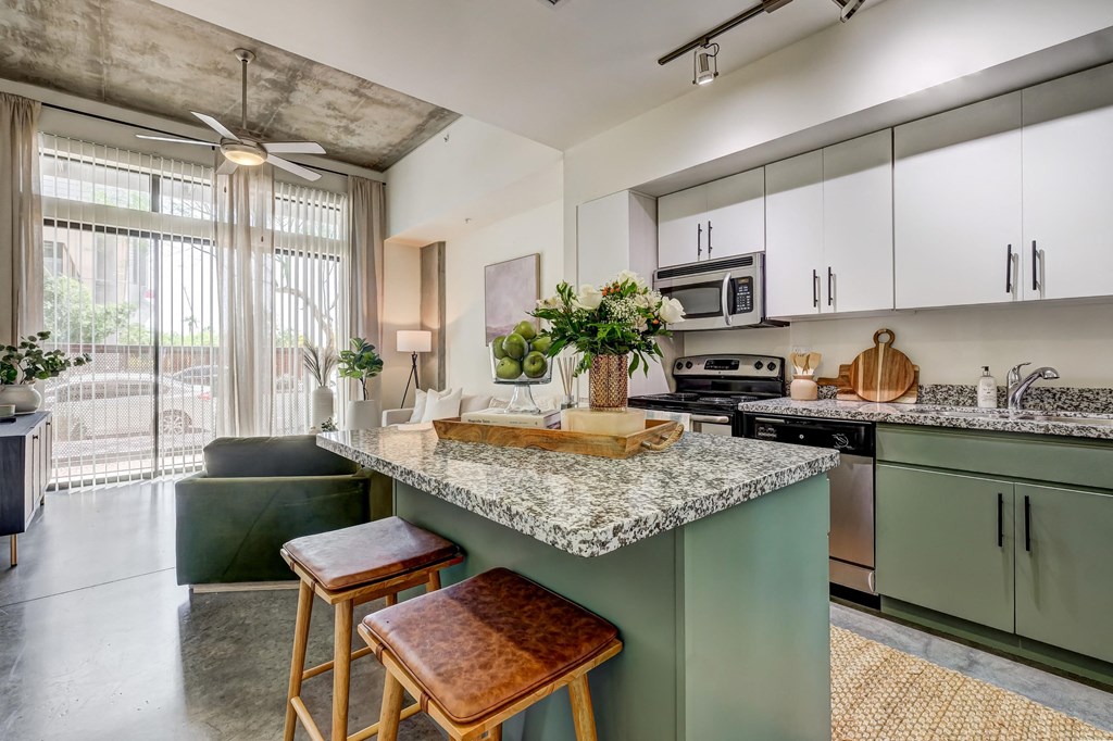 a kitchen with green cabinets and a counter top with three stools