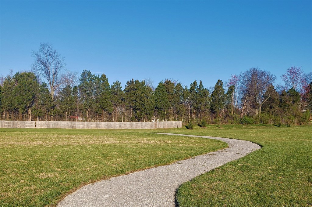 a path through a grassy field next to a fence