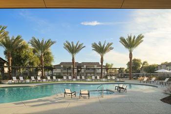 A pool surrounded by palm trees and lounge chairs.