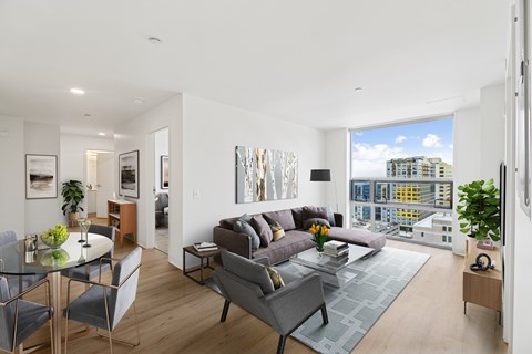 A modern living room with a grey couch and a glass table.