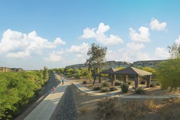 A gravel path with people walking down it and a gazebo in the distance.
