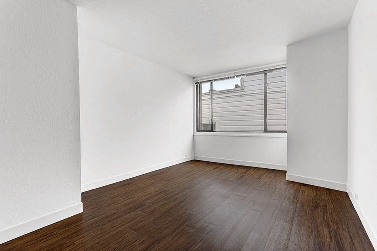 a bedroom with hardwood floors and a large window