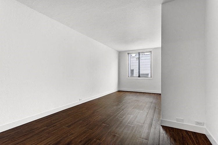 a bedroom with hardwood floors and a window