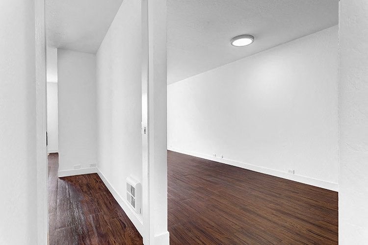an empty room with white walls and wood floors