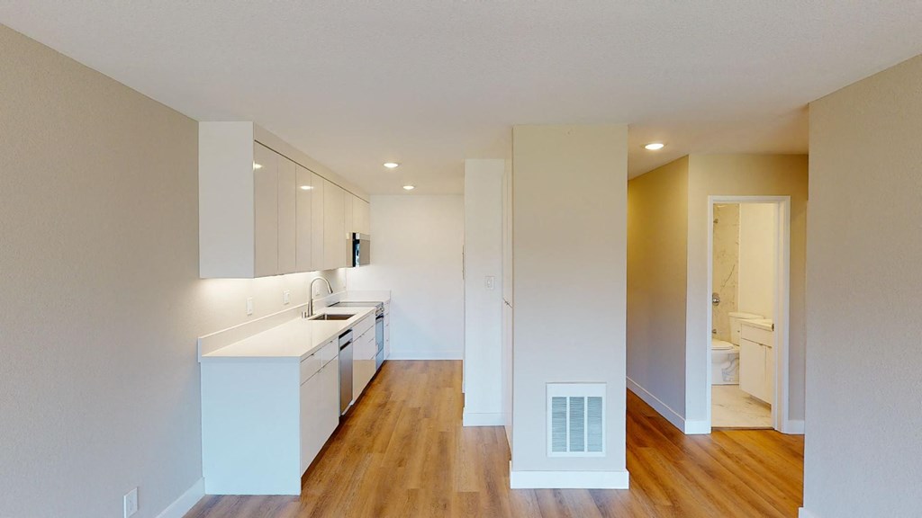 a kitchen with white cabinets and a wooden floor