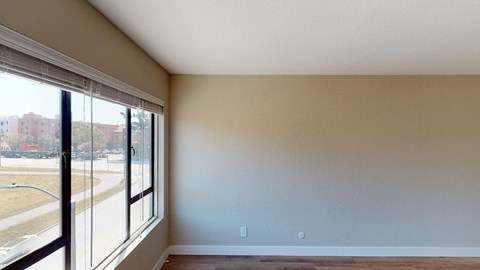 a bedroom with a large window and hardwood floors