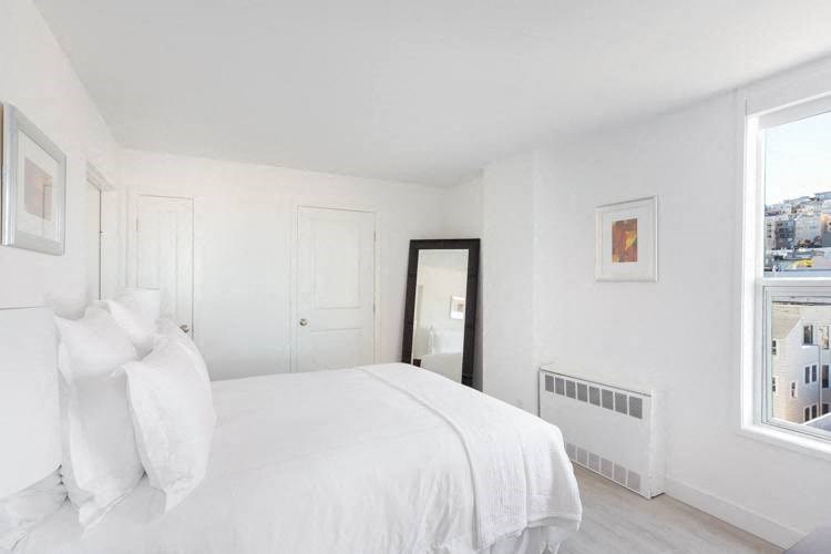 a white bedroom with a large window and a large bed