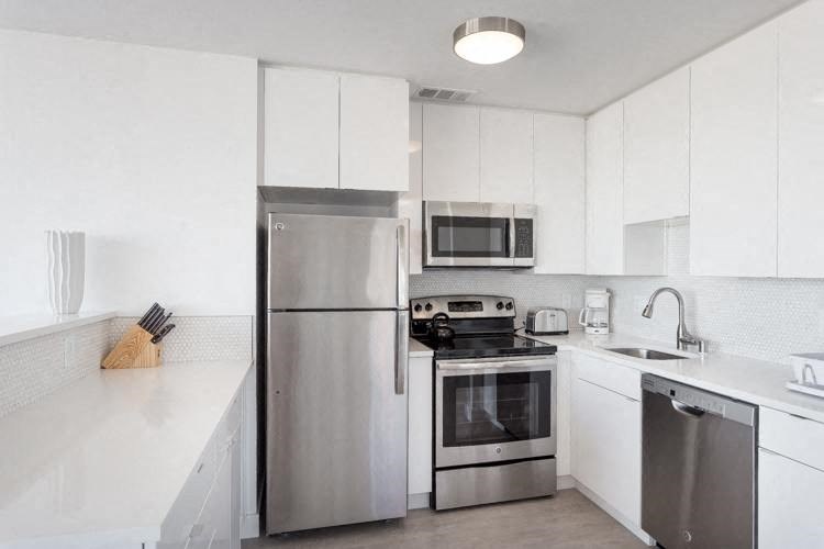 a kitchen with white cabinets and stainless steel appliances