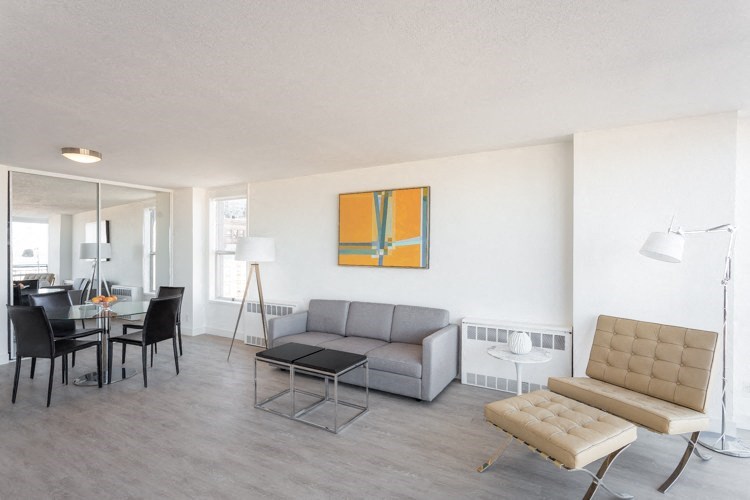 a living room with a gray couch and a yellow painting on the wall