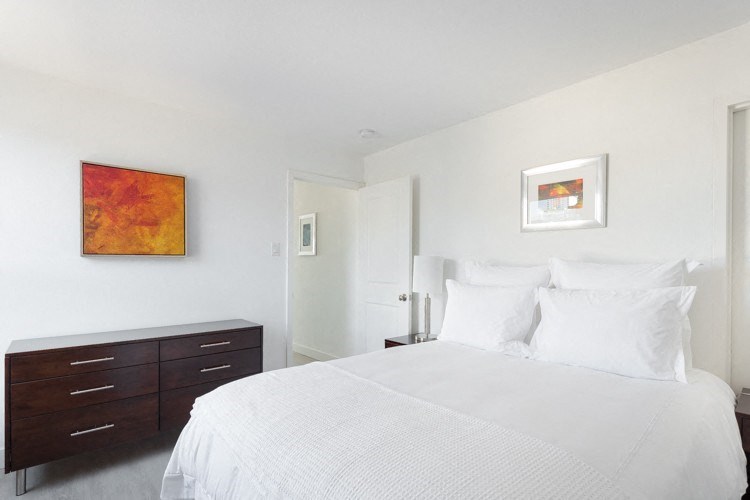 a bedroom with white walls and a large white bed