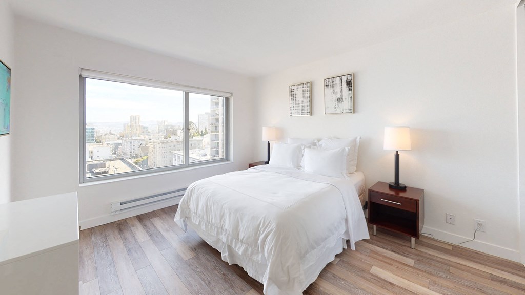 a bedroom with a large window and hardwood floors