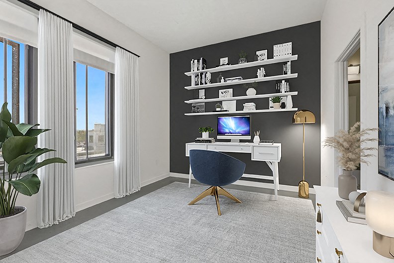 a home office with a desk and a computer in a room with windows