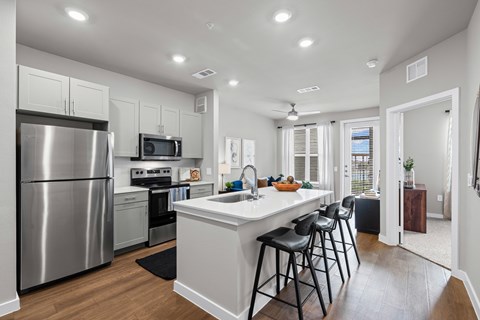 A modern kitchen with a large island and stools.