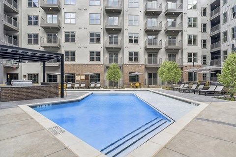 A large swimming pool in front of a multi-story apartment building.